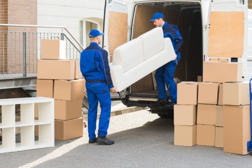 A large moving truck parked outside a house with furniture being loaded